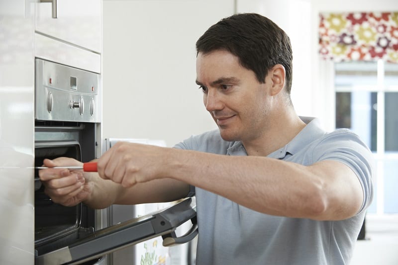Man fitting a built-in oven in a kitchen
