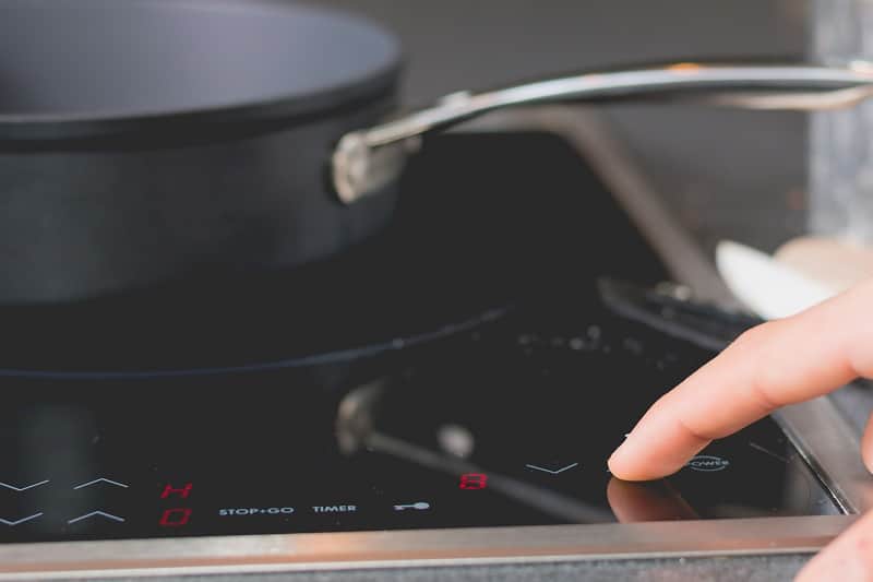 Finger touching button on induction hob