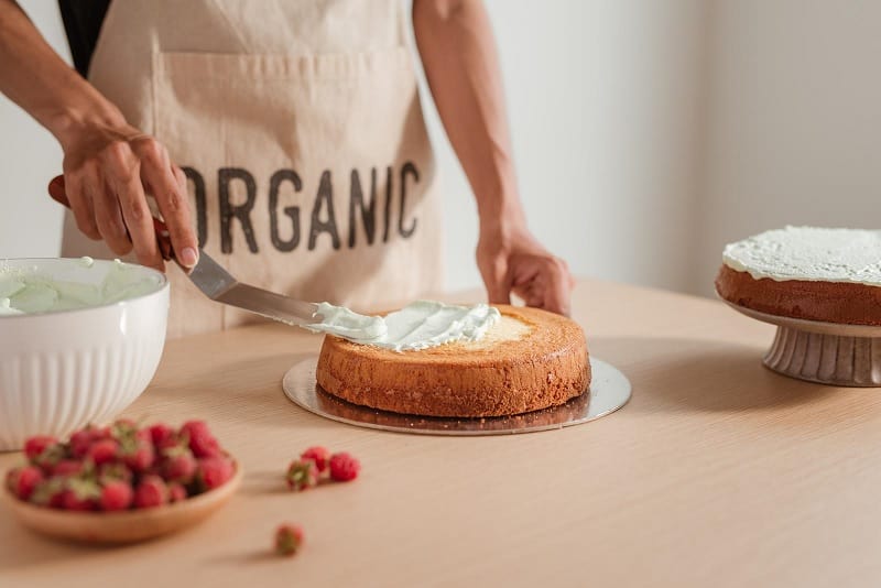 Baker putting icing on sponge cake