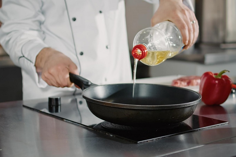 Chef pouring oil into pan