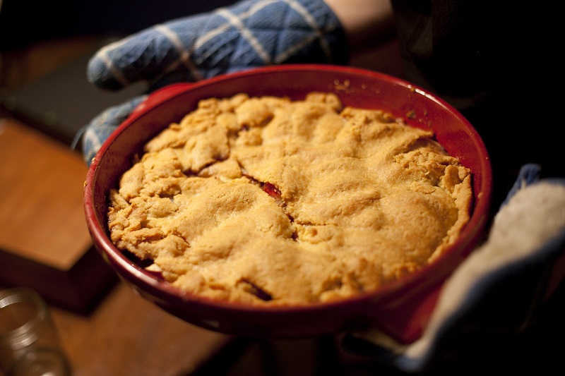 Holding cherry pie with oven gloves