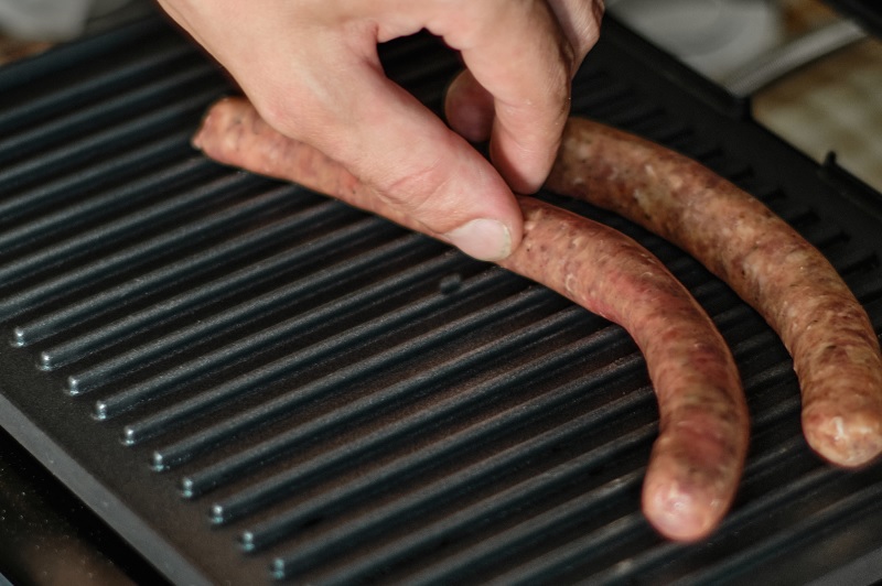 Laying sausages on grill
