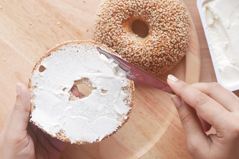 Spreading cream cheese on a bagel